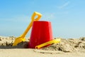 Red Bucket and yellow spade on sandy beach Royalty Free Stock Photo