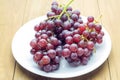 Red bunch grape in white dish on wooden board Royalty Free Stock Photo