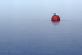 Red buoy frozen in ice on the blue water in a lake or the sea, a Royalty Free Stock Photo