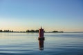 Red buoy on the water. A seagull sits on a lighthouse