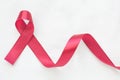 Red burgundy ribbon on white fabric background with copy space, symbol of Multiple Myeloma or Plasma cell cancer awareness. Royalty Free Stock Photo