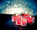 Red burning heart shaped candles on blue hearts bokeh Royalty Free Stock Photo