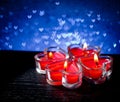 Red burning heart shaped candles on blue hearts bokeh Royalty Free Stock Photo