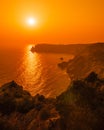 A red burning sunset with the silhouett of a cliff over the sea