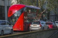 Red bus moving with cars on road in city during sunny day