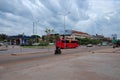 Red bus traveling along a city street, street traffic, cloudy evening