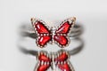 Red butterfly finger ring with reflection on grey background Royalty Free Stock Photo