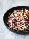 Red cabbage, carrot, cabbage coleslaw salad on black plate on grey background Royalty Free Stock Photo