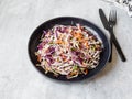 Red cabbage, carrot, cabbage coleslaw salad on black plate on grey background Royalty Free Stock Photo