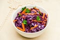 Red cabbage salad with carrots and parsley in a white bowl on a linen tablecloth. Vegetarian healthy food. Diet concept Royalty Free Stock Photo