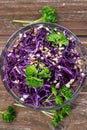 Red cabbage salad with parsley sprinkled with nuts, wooden background, top view Royalty Free Stock Photo