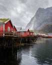 Red cabins perched atop a dock on a tranquil lake surrounded by lush mountains. Royalty Free Stock Photo