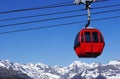 Red cable car and snowed mountain peaks