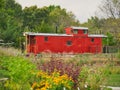 Red caboose in with dense trees and plants in Overland Park Arboretum & Botanical Gardens
