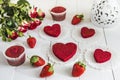 Red cake without cream `red velvet` on a white wooden table, decorated with strawberries, roses and white openwork vase with a hea Royalty Free Stock Photo