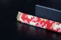 Red camouflage seed beads bracelet on a dark background Royalty Free Stock Photo