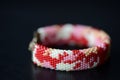 Red camouflage seed beads bracelet on a dark background Royalty Free Stock Photo