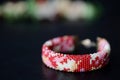 Red camouflage seed beads bracelet on a dark background Royalty Free Stock Photo