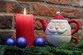 Red candle, blue christmas balls and Santa Claus teapot Royalty Free Stock Photo