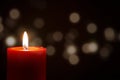 Red Candle with fire against defocused lights in darkness with golden bokeh in the dark Background Royalty Free Stock Photo