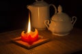 Red candle illuminates a jug and a cup Royalty Free Stock Photo