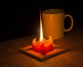 Red candle illuminates a mug Royalty Free Stock Photo