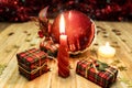 Red candle lit next to some packages of gifts and a red ball of Christmas ornament Royalty Free Stock Photo