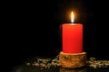 Red candle in wood handmade candlestick with ash on black background.