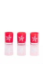3 red candles, candle holders with crystal snowflakes isolated on reflective white perspex background with copy space
