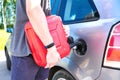 Red canister in the hands of a man. Filling a stalled car with gasoline from a canister
