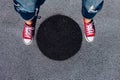 Red canvas sneakers shoes on woman`s feet on the asphalt with black circle Royalty Free Stock Photo