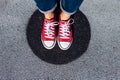 Red canvas sneakers shoes on woman`s feet on the asphalt with black circle Royalty Free Stock Photo