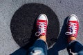 Red canvas sneakers shoes on woman`s feet on the asphalt with black circle Royalty Free Stock Photo