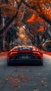 Red sports car zooms down treelined road with sleek hood and bright tail lights Royalty Free Stock Photo