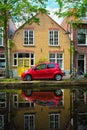 Red car on canal embankment in street of Delft. Delft, Netherlands Royalty Free Stock Photo