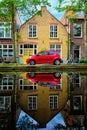 Red car on canal embankment in street of Delft. Delft, Netherlands Royalty Free Stock Photo