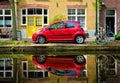 Red car on canal embankment in street of Delft. Delft, Netherlands Royalty Free Stock Photo