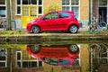 Red car on canal embankment in street of Delft. Delft, Netherlands Royalty Free Stock Photo