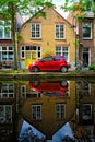 Red car on canal embankment in street of Delft. Delft, Netherlands Royalty Free Stock Photo