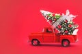 Red Car Carrying Christmas Tree on a Red Background. Christmas Background Royalty Free Stock Photo