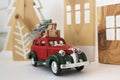 Red car with a Christmas tree and New Year\'s gift boxes. handmade wooden toys in the Scandinavian style as a background Royalty Free Stock Photo