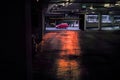 Red car driving past supermarket indoor car park at sunset