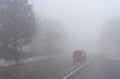 Red Car Driving in Thick Fog