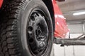 Red car on an elevator or hoist in a repair workshop or garage with focus to wheel. Automobile service station Royalty Free Stock Photo