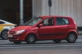 Red car Hyundai Getz in motion on the city road. Man in black sungrasses driving hatchback car. Fast moving vehicle with blurred Royalty Free Stock Photo