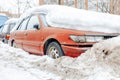 Red car parked in snowdrift. Old rusty auto covered in snow. Wheel stuck in the deep snow Royalty Free Stock Photo