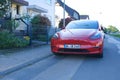 red car parked on street, popular passenger electric vehicle from American company Elon Musk, concept environmental minimizing,