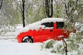 Red car in a parking lot, covered with snow during a snowfal