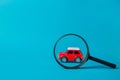 Red car peeked out with a magnifying glass on blue background. Technical inspection and machine search concept Royalty Free Stock Photo