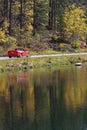 Red car refletcs in the waters at fall